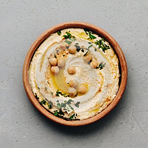 Large bowl of homemade hummus garnished with chickpeas, red sweet pepper, parsley and olive oil