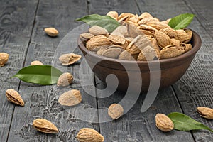 A large bowl of shelled almonds on a black table