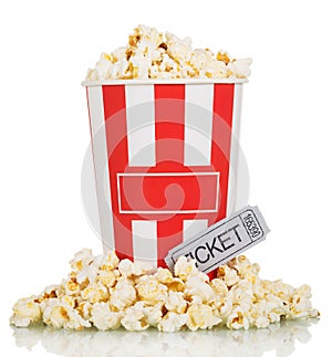 Large box full popcorn and popcorn around movie ticket on white.