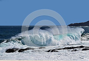 Large breaking wave hitting the shoreline with a big splash