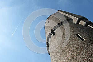 Large brick tower and airplane flying in the blue sky