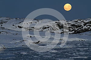 Large bright moon over the Antarctic islands covered with snow o