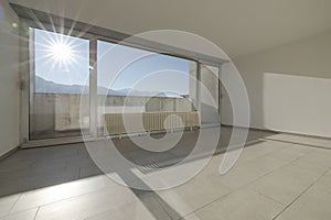 Large bright window with direct sun entering the room overlooking the Swiss mountains