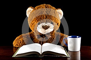 Large Brown Teddy Bear Reading at a Table With Mug of Tea or Coffee