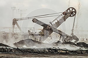 Large bucket excavator works in a hot outdoors dump. Heavy industry.