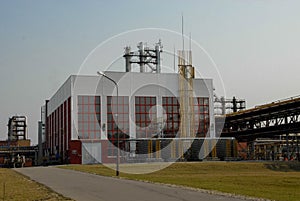 Large building with production equipment with pipes, pumps, compressors and distillation columns at a petroleum refining