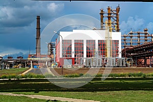 Large building with production equipment with pipes, pumps, compressors and distillation columns at a petroleum refining