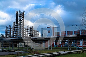 Large building with production equipment with pipes, pumps, compressors and distillation columns at a petroleum refining