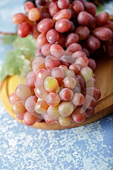 Large bunch fresh pink red grapes on wooden board