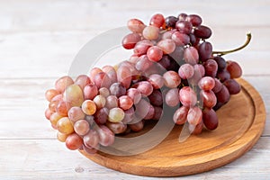 Large bunch fresh pink red grapes on wooden board