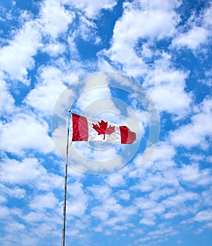 Large Canadian Flag flying against  blue sky background