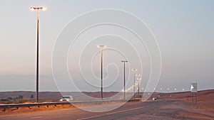 large car road in desert in UAE in evening, automobiles moving on highway with illumination