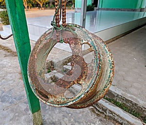 A large car tire rim that has been converted into a school bell