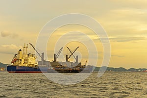 Large cargo ship for logistic import export goods anchor at sea in evening with golden sunset