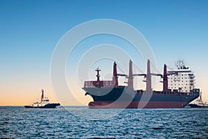 large carrier ship floating afternoon in sea, tugboat dragging container ship, blue sky evening background and sea front