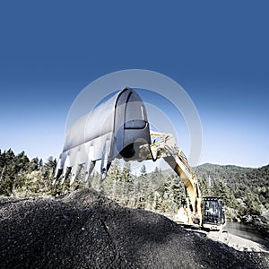 Large chain shovel excavator dredging a storage pond in the wooded Alps