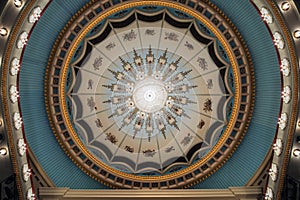 Large chandelier hangs on the theater hall decorated ceiling