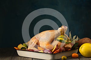 A large chicken stuffed with an apple with vegetables and citrus fruits, ready for baking, copy space