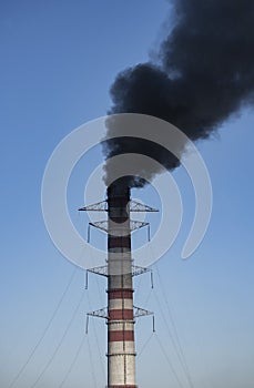 Large chimney of a thermal power plant with a stream of black smoke