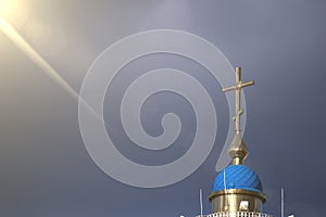 A large Christian cross on which falls a ray of sun through the clouds