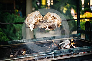 Large chunk of pork cooking on open fire, flame outdoors