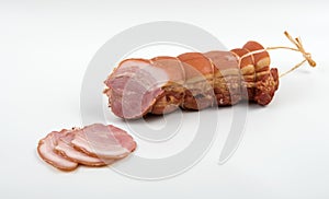 Large chunk of pork delicacy in a spice sprinkle with slices on a white background
