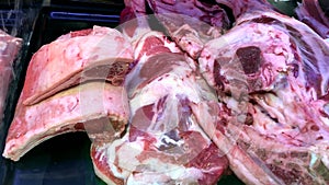 Large chunks of fresh pork behind glass on the counter in the supermarket