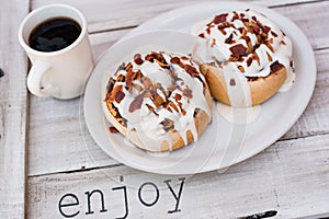 Large bacon cinnamon rolls with a cup of coffee photo