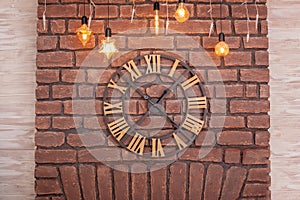 Large classic Clock with roman numerals on a red brick wall. Vintage Clock on wall with glowing garland. Interior concept. Metal w