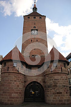 a large clock tower in the middle of an alley near buildings