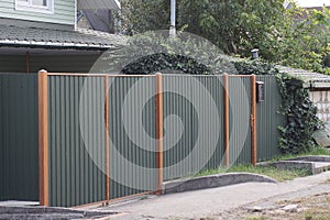 Large closed metal green gate and door on the fence