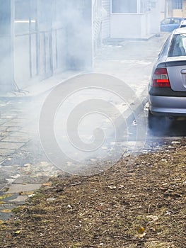 A large cloud of gray smoke from the exhaust pipe of a car in the courtyard of a residential building