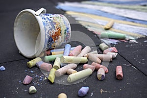 Large colored street chalk. Plastic bucket with sidewalk chalk with creative drawing of child in background