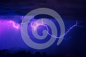 Large colorful cloud lightning streaks across the sky in a storm