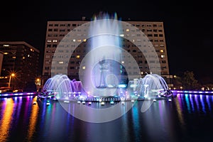 large colorful fountain in front of large hotel at night on lake