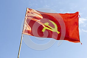 Large communist flag floating in the wind with a blue sky