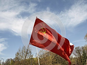 Large communist flag floating in the wind with a blue sky background