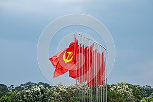 Large communist flags floating in the wind with a blue sky background