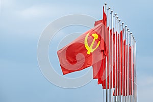 Large communist flags floating in the wind with a blue sky background