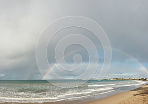 large complete full half circle rainbow stretching across the sky into the ocean at Apollo Bay, Victoria, Australia