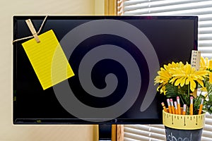 Large computer monitor with yellow reminder note clipped to left