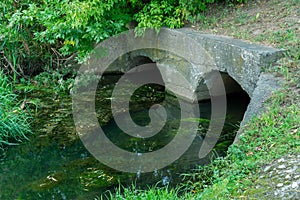 A large concrete pipe for diverting the river under the highway. Leaky dirty water from large concrete pipes. Dirty sewage from