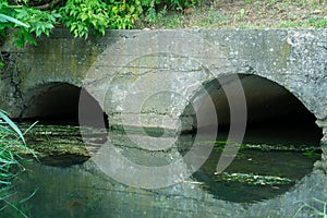 A large concrete pipe for diverting the river under the highway. Leaky dirty water from large concrete pipes. Dirty sewage from