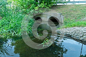 A large concrete pipe for diverting the river under the highway. Leaky dirty water from large concrete pipes. Dirty sewage from