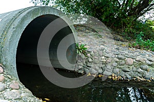 A large concrete pipe for diverting the river under the highway. Leaky dirty water from large concrete pipes. Dirty sewage from