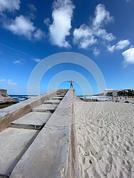 A large concrete staircase and a person thanking nature for the beauty of a beautiful beach on a sunny day, blue sky in a