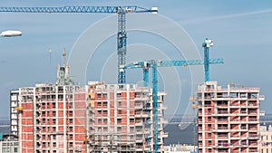 Large construction site including several cranes working on a building big complex, with cloudy sky timelapse