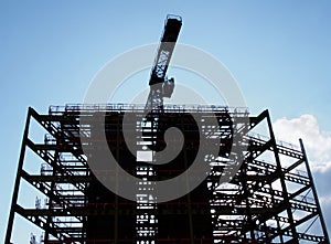 Large construction site in silhouette in the evening with steel girders and a crane in silhouette against a blue cloudy sky