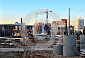 Large construction site with working cranes and heavy machinery for road works, wheel loader, bulldozer, excavator.