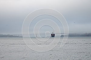 large container cargo ship entering the port of San Francisco through the bridge and fog